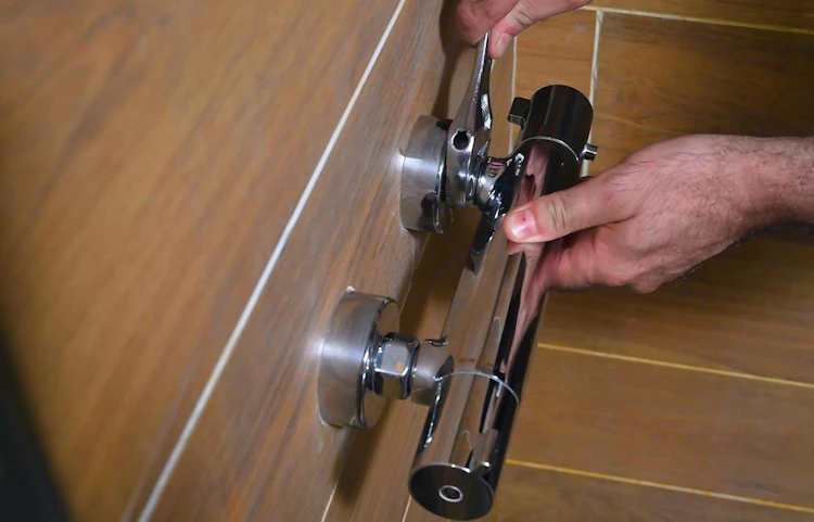 Mains ajustant une vanne thermostatique chromée sur carrelage bois