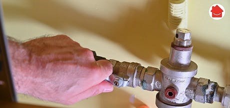 Main manipulant une vanne d'arrêt sur tuyauterie murale