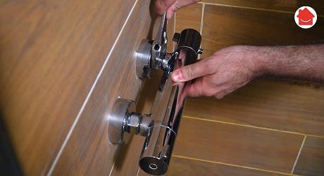 Mains réglant une tête thermostatique chromée sur un tuyau