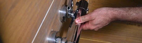 Mains réglant une tête thermostatique chromée sur un tuyau