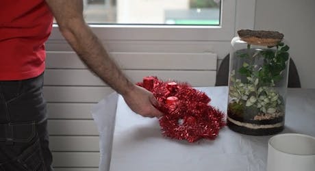 Main posant une décoration florale rouge sur une table