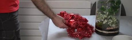 Main posant une décoration florale rouge sur une table