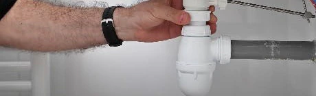 Main serrant le siphon sous un lavabo de salle de bain