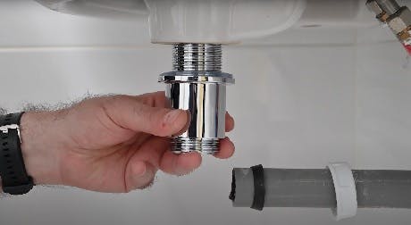 Main tenant un raccord chromé sous un lavabo