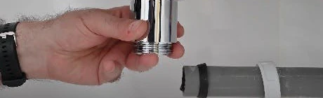 Main tenant un raccord chromé sous un lavabo