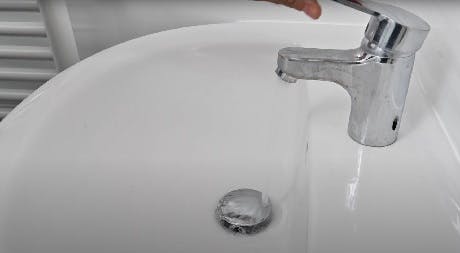 Robinet de lavabo ouvert avec filet d'eau qui coule
