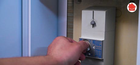 Main tournant un bouton de réglage sur un boîtier technique mural