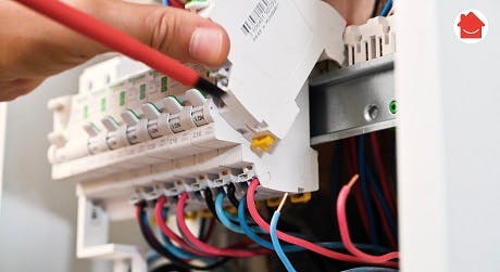 Main branchant un connecteur sur des fils dans un tableau électrique