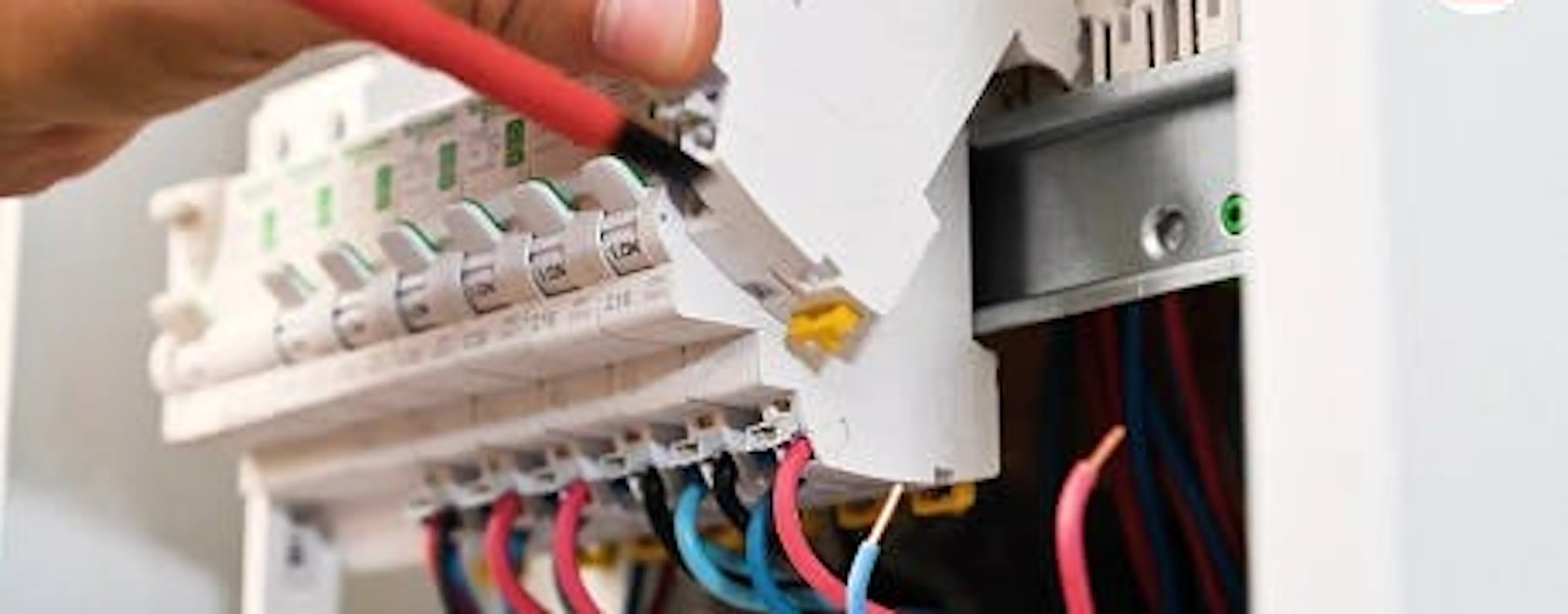 Main branchant un connecteur sur des fils dans un tableau électrique