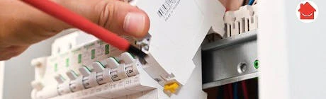 Main branchant un connecteur sur des fils dans un tableau électrique