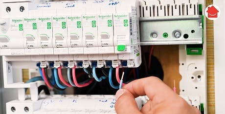 Main manipulant des disjoncteurs dans un tableau électrique Schneider