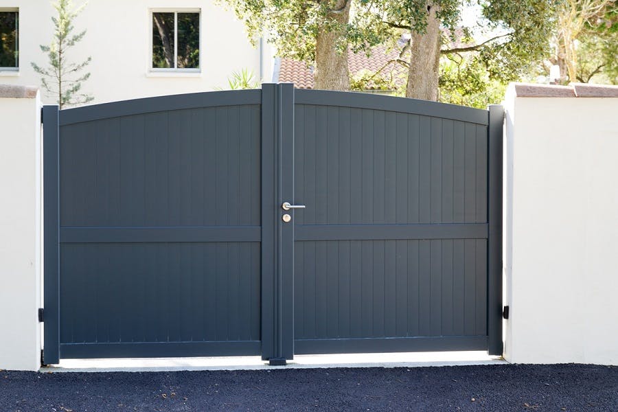 Portail double anthracite en aluminium devant une maison blanche