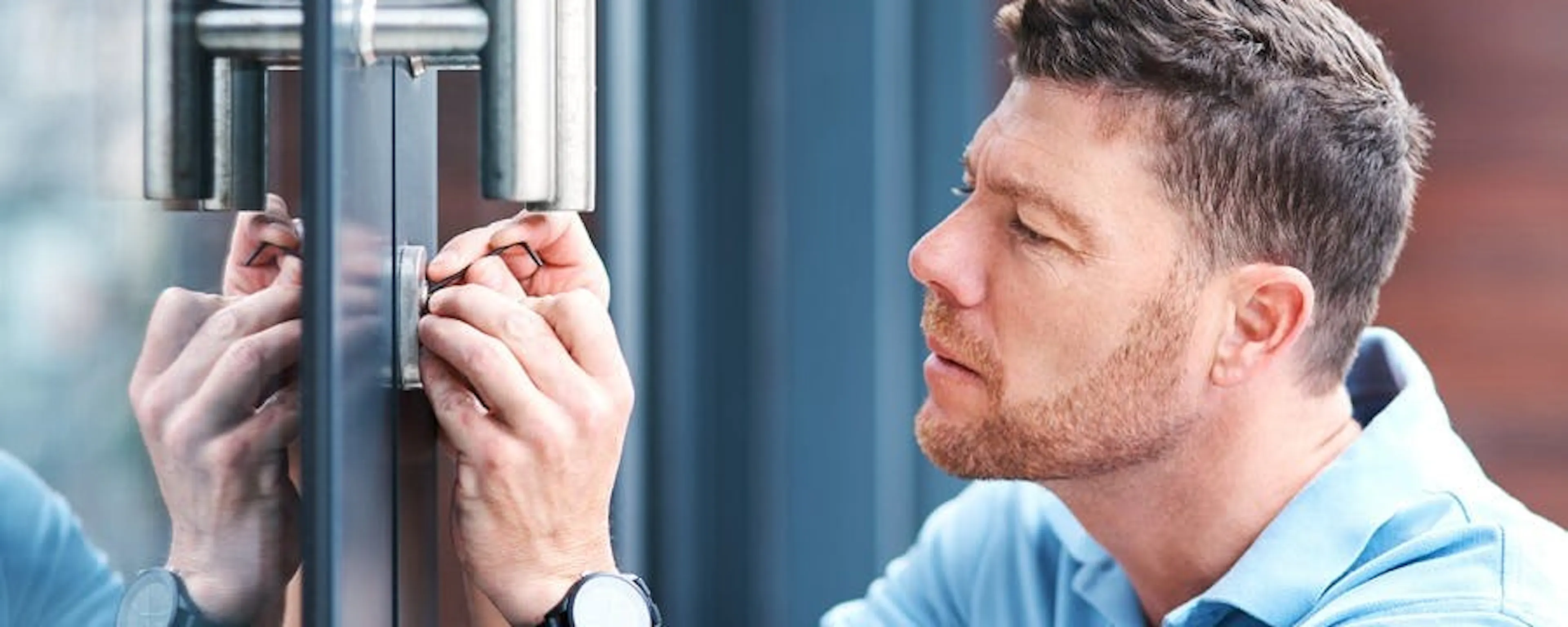 Technicien en train d'inspecter et de dégripper une serrure sur une porte en aluminium