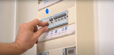 Main actionnant un disjoncteur dans un tableau électrique