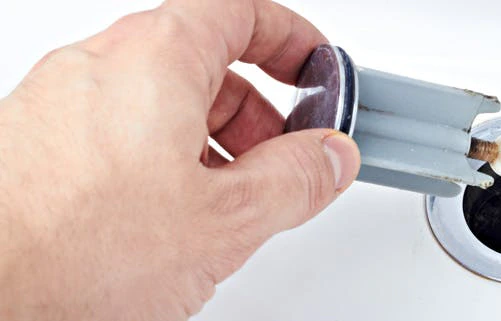 Main tenant le siphon chromé d'un lavabo à déboucher