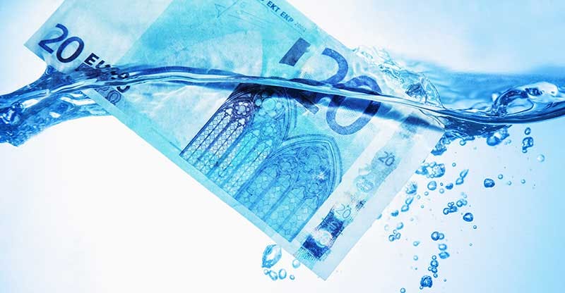 Billet de vingt euros submergé dans de l'eau bleue avec des bulles