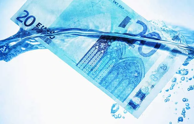 Billet de vingt euros submergé dans de l'eau bleue avec des bulles