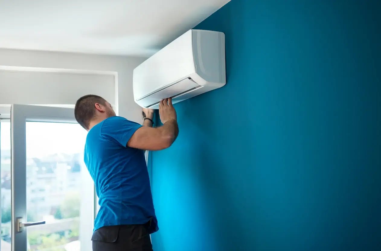 Technicien installant une climatisation murale bleue