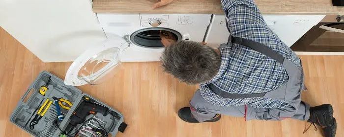 Technicien en salopette réparant un appareil électroménager