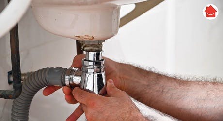 Plombier serrant le siphon sous un lavabo de salle de bain