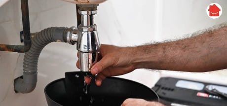 Main resserrant le raccord du siphon sous un lavabo