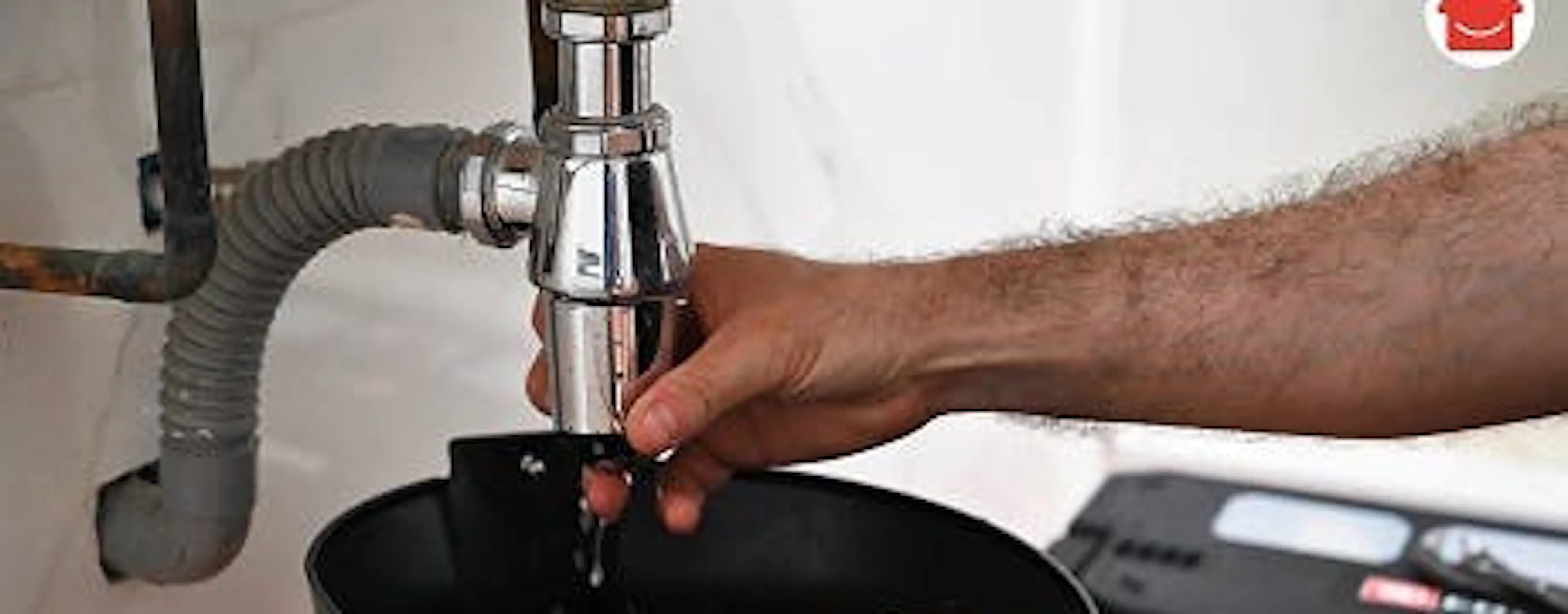 Main resserrant le raccord du siphon sous un lavabo