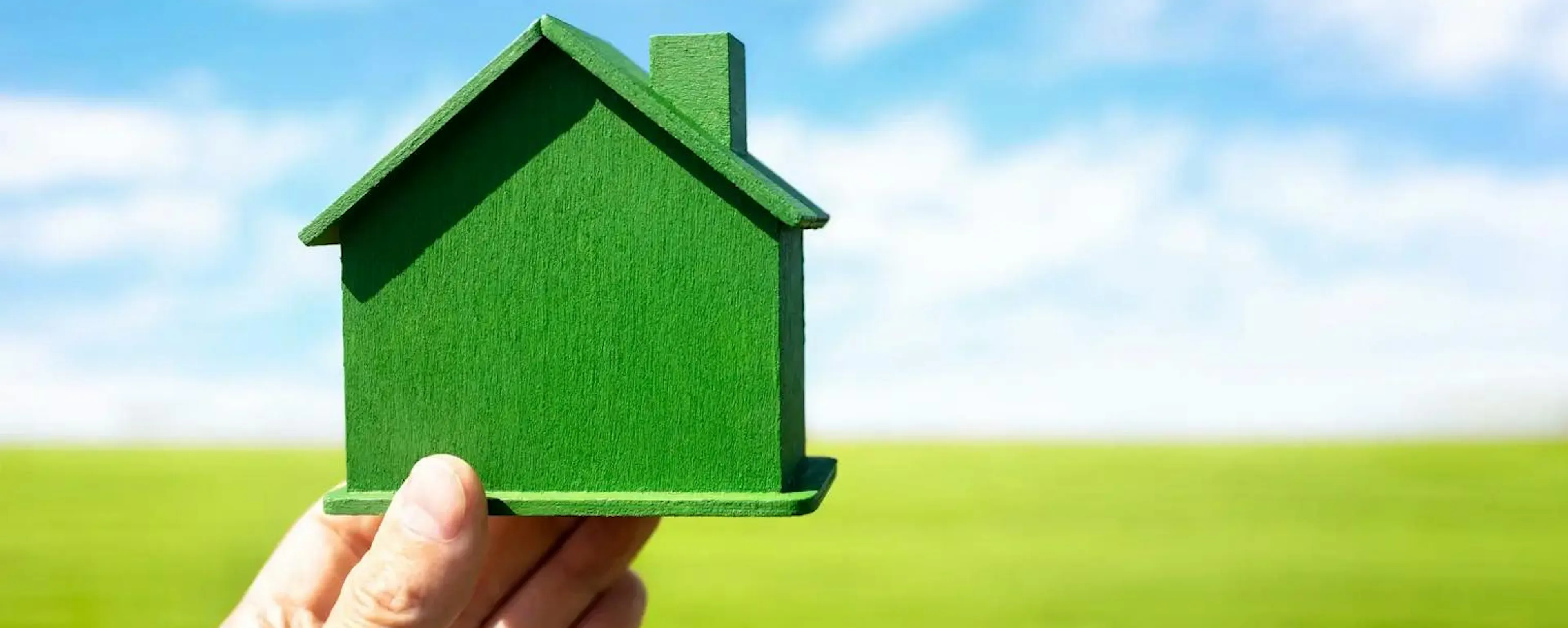 Main tenant une maquette de maison verte sumbolisant l'optimisation de la consommation énergétique de son logement