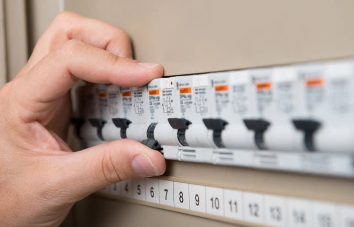 Main actionnant des disjoncteurs dans un tableau électrique