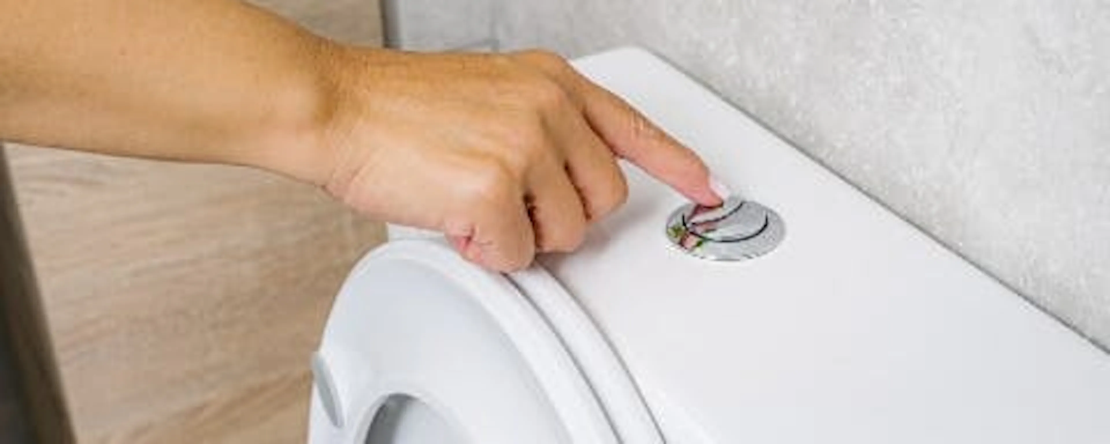 Main appuyant sur le bouton de chasse d'eau des toilettes pour économiser l'eau du robinet