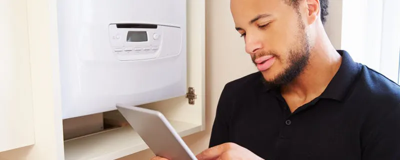 Technicien consultant une tablette lors de l'entretien annuel d'une chaudière à gaz