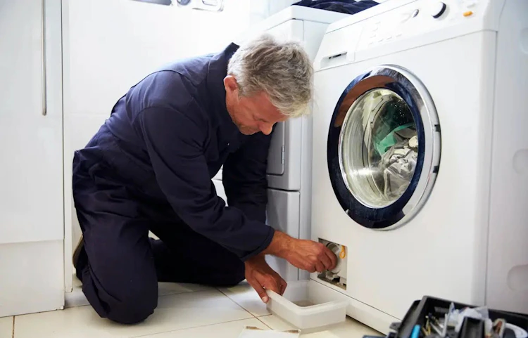 Technicien réparant une machine à laver à domicile
