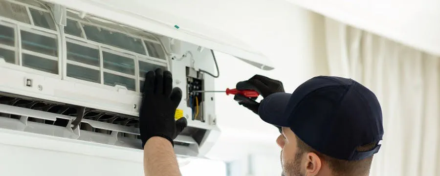 Technicien réparant une unité de climatisation murale intérieure