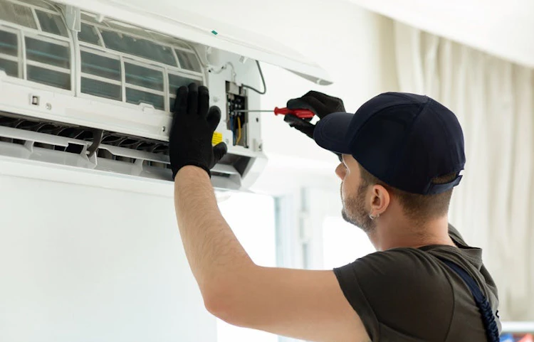 Technicien réparant une unité de climatisation murale intérieure
