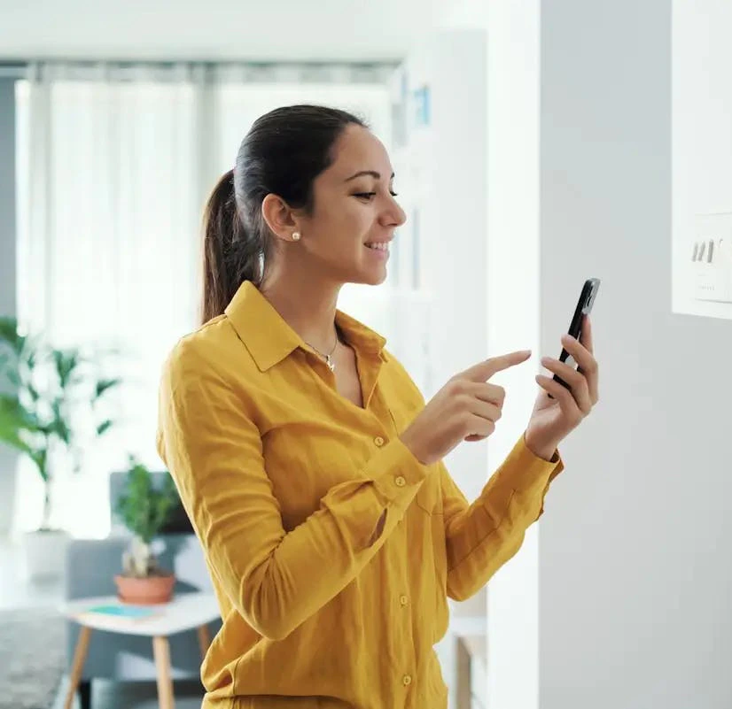 Femme en jaune contrôlant sa chaudière avec son smartphone
