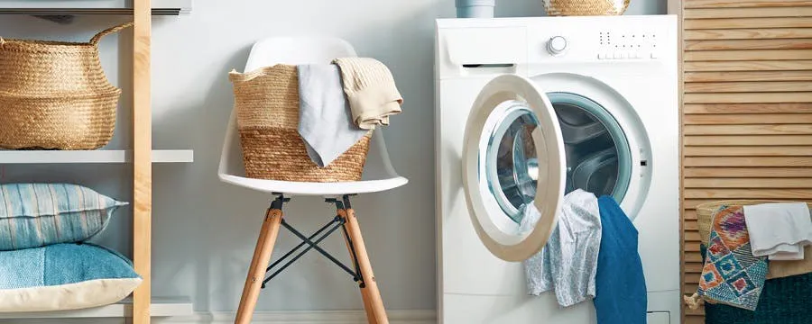 Machine à laver qui fuit avec linge dans une buanderie décorée de paniers en osier
