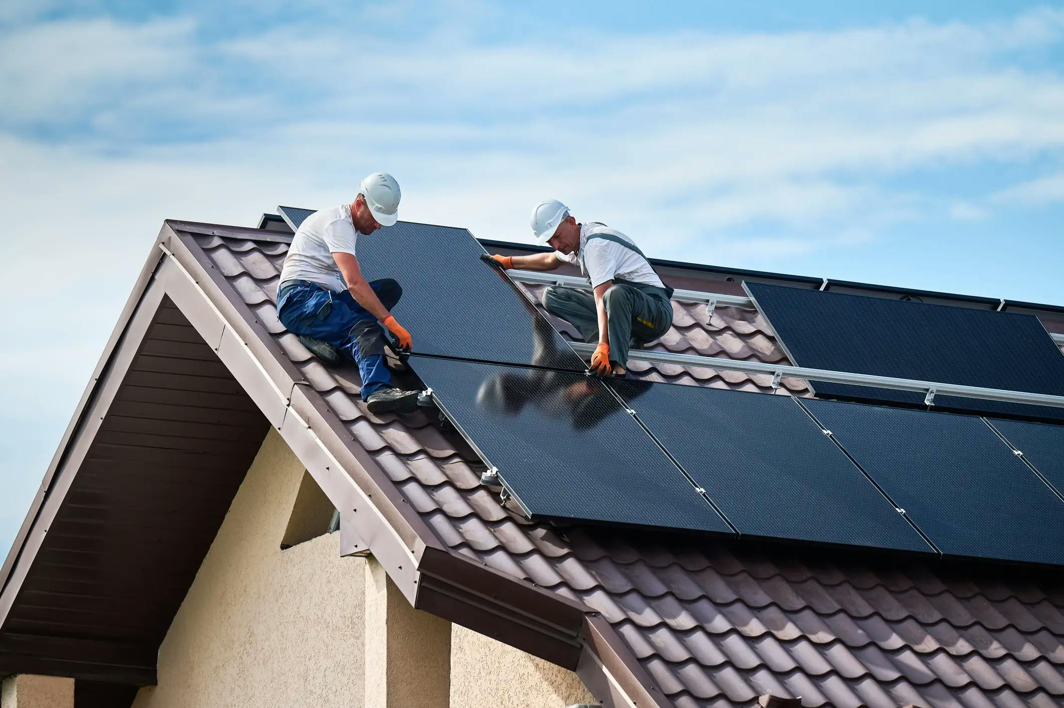 Deux ouvriers installant des panneaux solaires sur un toit