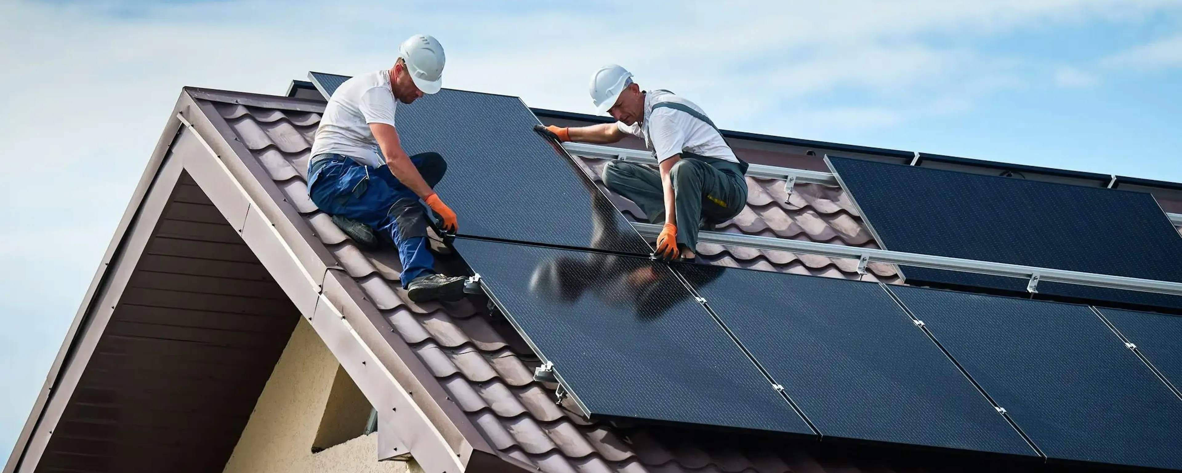 Deux ouvriers installant des panneaux solaires sur un toit