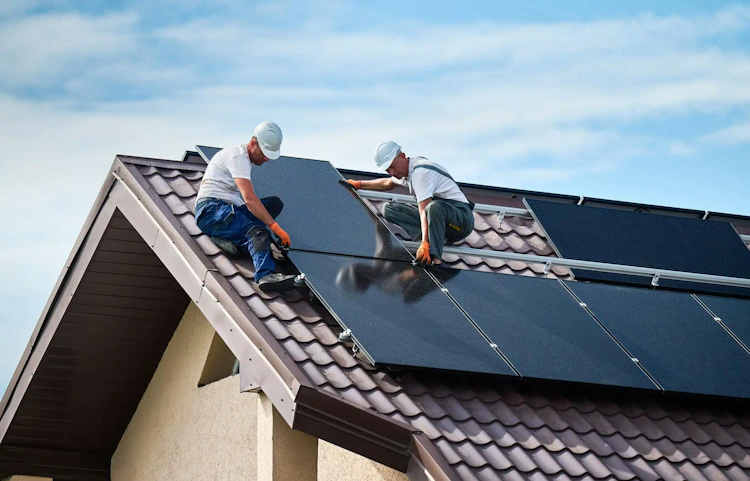 Deux ouvriers installant des panneaux solaires sur un toit