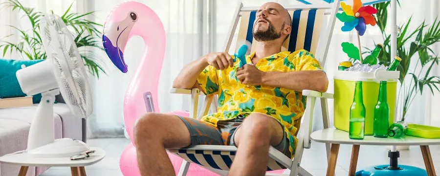 Homme se rafraîchissant avec un ventilateur dans son salon pour faire face aux fortes chaleurs