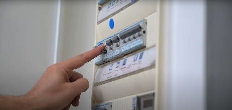 Doigt pointant un disjoncteur dans un tableau électrique