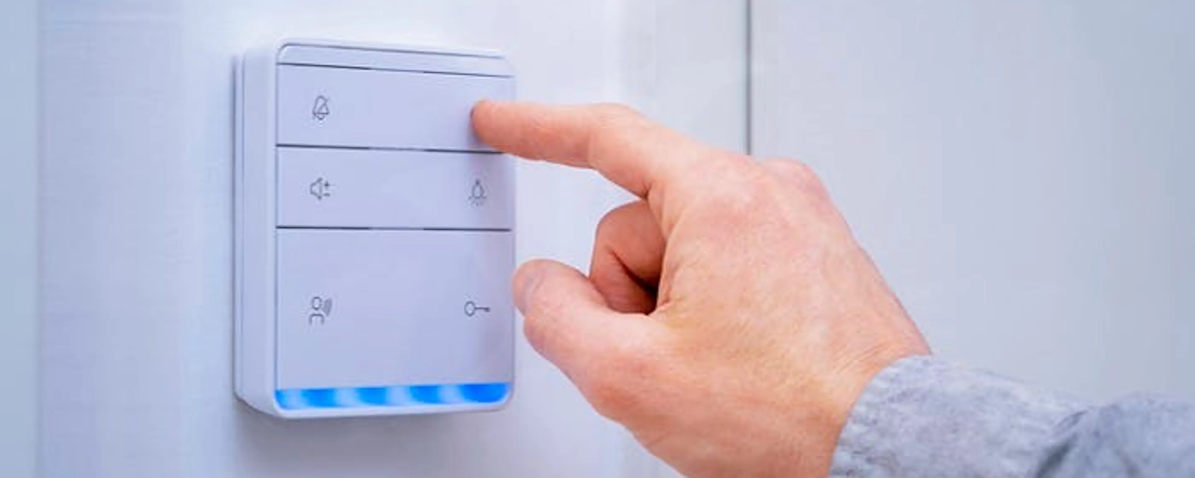Main appuyant sur un interrupteur sans fil domotique blanc avec LED bleues à installer chez soi
