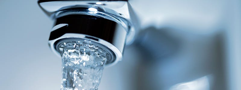 Gros plan d'un jet d'eau coulant d'un robinet chromé