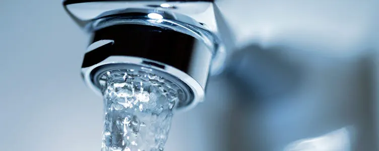 Gros plan d'un jet d'eau coulant d'un robinet chromé équipé d'un mousseur