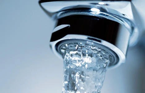 Gros plan d'un jet d'eau coulant d'un robinet chromé