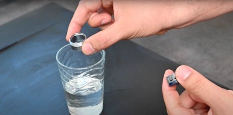 Main trempant un joint de robinet dans un verre d'eau