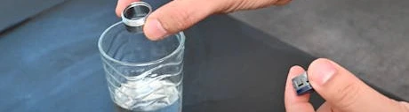 Main trempant un joint de robinet dans un verre d'eau