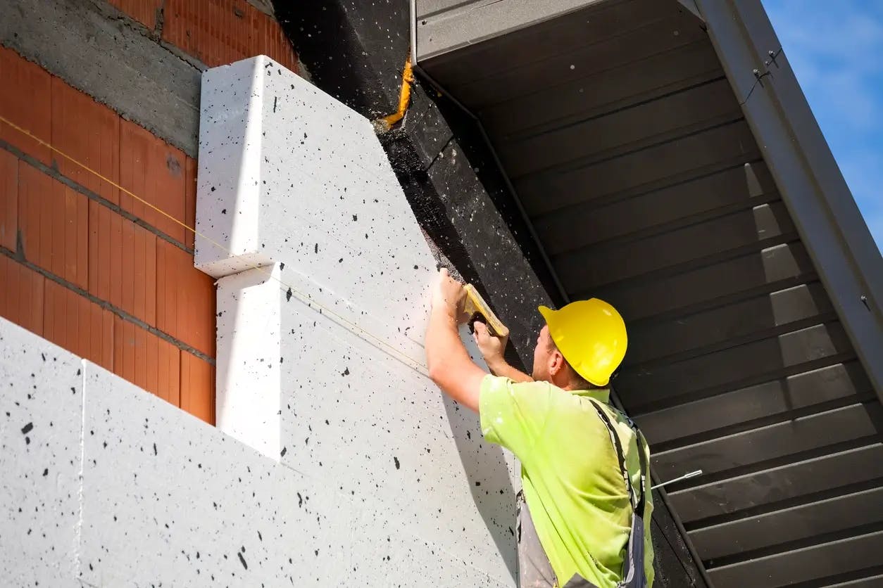 Ouvrier posant des panneaux isolants sur façade de bâtiment