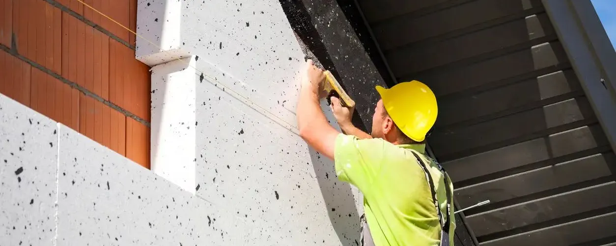 Ouvrier posant des panneaux sur façade afin d'isoler les murs par l'extérieur