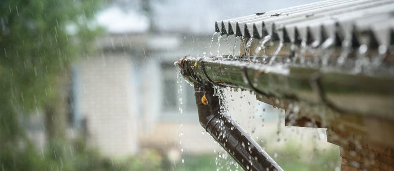 Gouttière débordant sous une forte pluie sur une maison