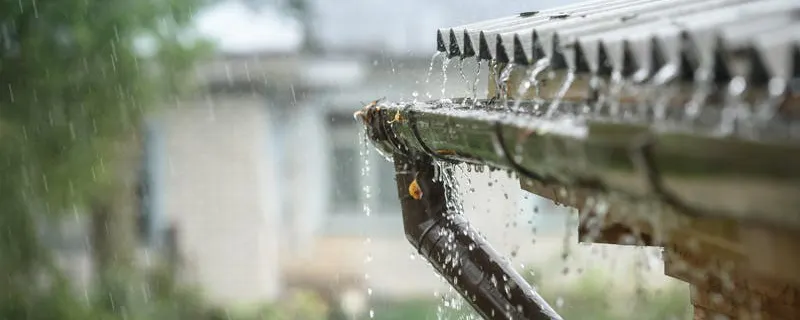 Gouttière débordant d'eau de pluie qui pourrait être récupéré par un récupérateur d'eau de pluie